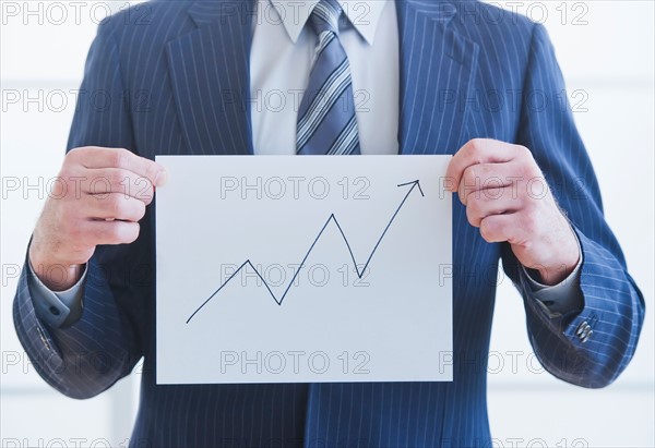 Man wearing suit holding chart. Photo : Daniel Grill