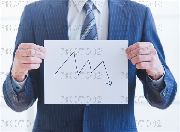 Man wearing suit holding chart. Photo : Daniel Grill