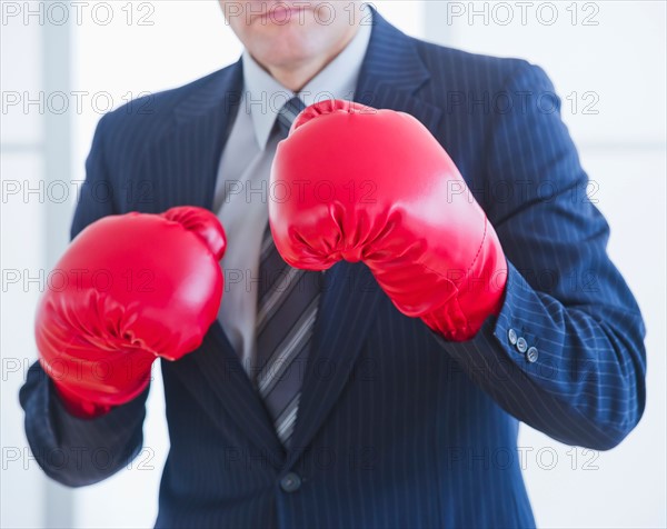 Businessman wearing red boxing gloves. Photo : Daniel Grill