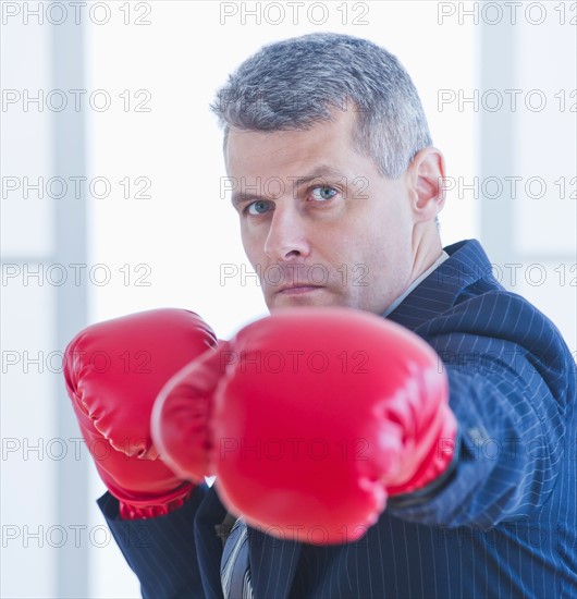 Businessman wearing red boxing gloves. Photo : Daniel Grill