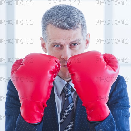 Businessman wearing red boxing gloves. Photo : Daniel Grill