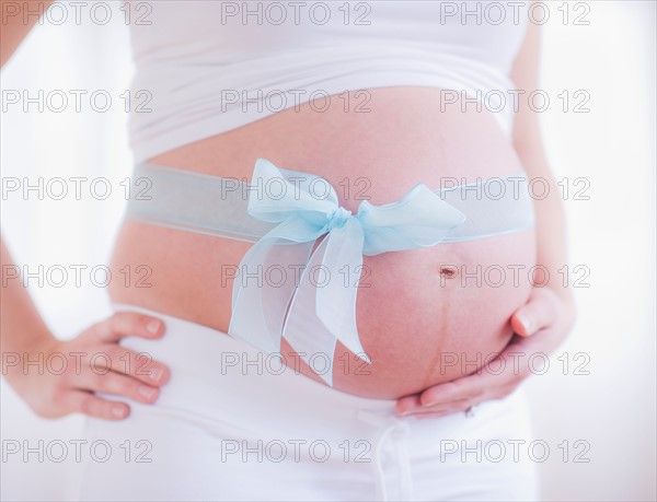Pregnant woman with blue ribbon on her belly. Photo : Daniel Grill