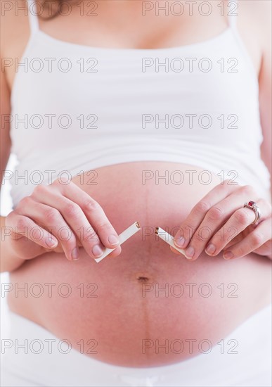 Pregnant woman holding broken cigarette. Photo : Daniel Grill