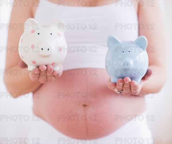 Pregnant woman holding two piggybanks. Photo : Daniel Grill