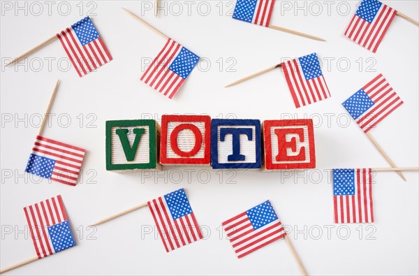 Studio shot of small american flags and wooden blocks with text VOTE . Photo : Winslow Productions