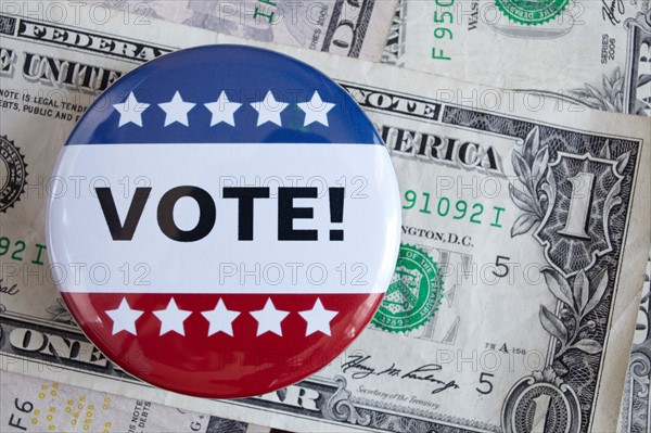 Studio shot of vote pin and one dollar banknotes. Photo : Winslow Productions