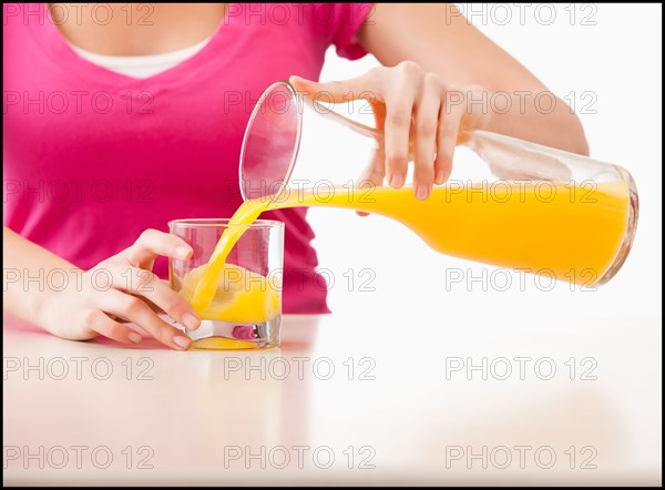 Young woman pouring juice into glass. Photo : Mike Kemp