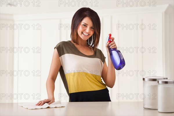 Young woman cleaning kitchen. Photo : Mike Kemp