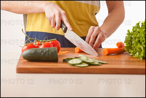 Young woman cutting vegetables. Photo : Mike Kemp