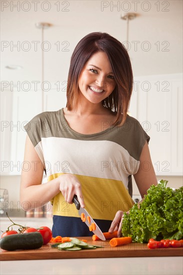 Young woman cutting vegetables. Photo : Mike Kemp