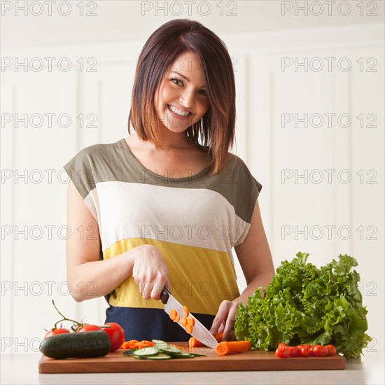 Young woman cutting vegetables. Photo : Mike Kemp