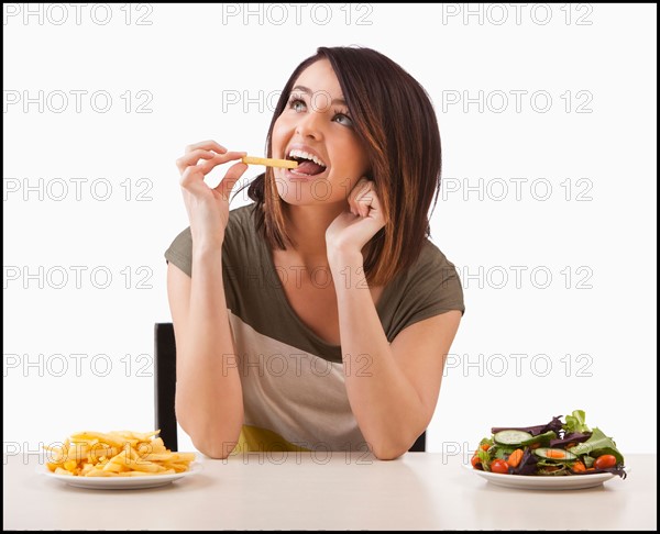 Young woman choosing between healthy and unhealthy food. Photo : Mike Kemp