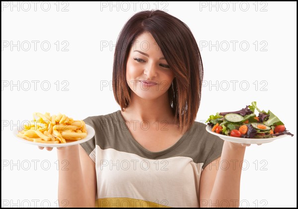 Young woman choosing between healthy and unhealthy food. Photo : Mike Kemp