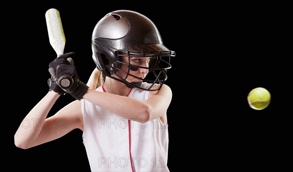 Girl (12-13) plying softball, studio shot. Photo : Mike Kemp