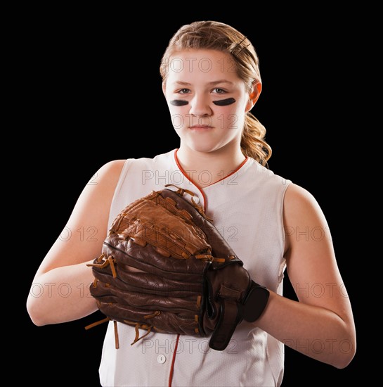 Portrait of girl (12-13) plying softball, studio shot. Photo : Mike Kemp