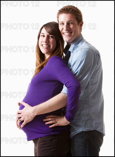 Man embracing pregnant woman, studio shot. Photo : Mike Kemp
