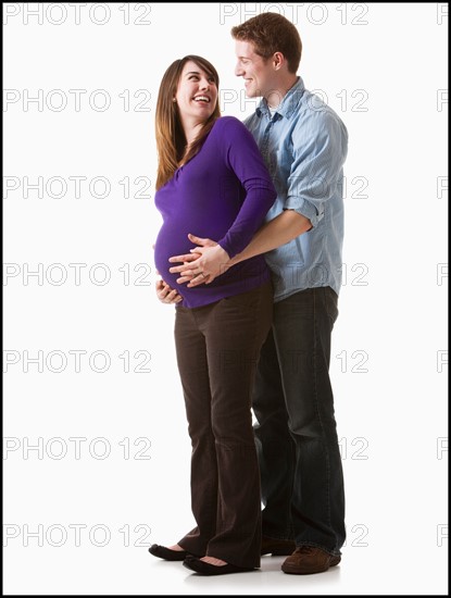 Man embracing pregnant woman, studio shot. Photo : Mike Kemp