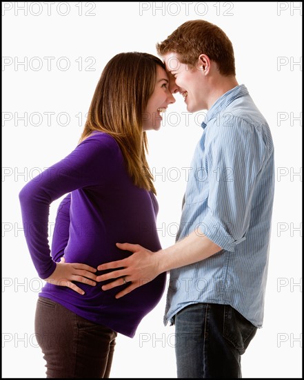 Man embracing pregnant woman, studio shot. Photo : Mike Kemp