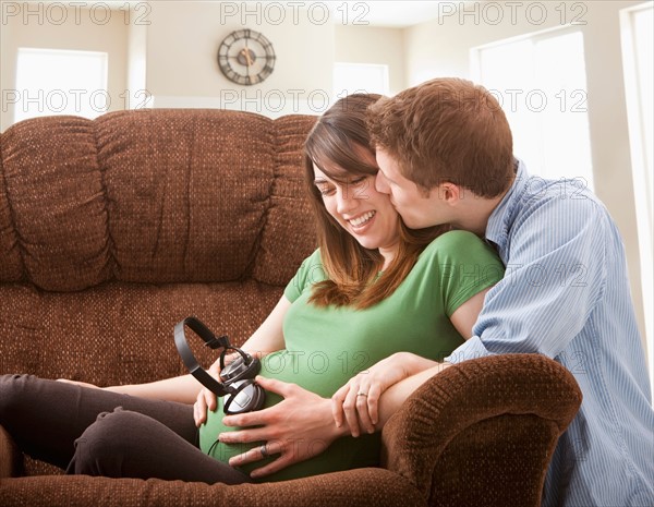 Pregnant woman with boyfriend holding headphones on belly. Photo : Mike Kemp