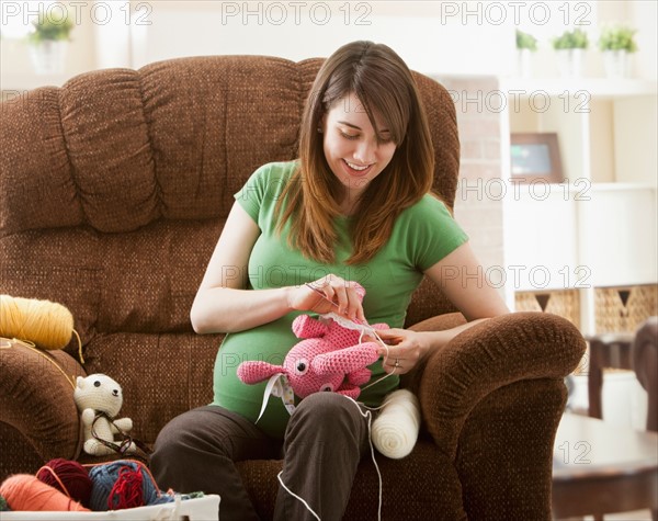 Portrait of pregnant woman preparing stuffed toys for baby. Photo : Mike Kemp