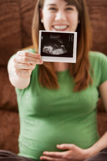 Portrait of pregnant woman showing ultrasonography scan. Photo : Mike Kemp