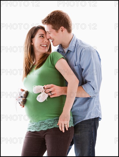 Man embracing pregnant woman, studio shot. Photo : Mike Kemp