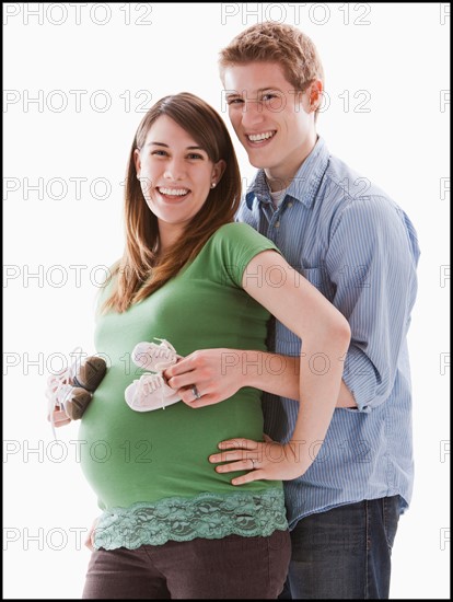 Man embracing pregnant woman, studio shot. Photo : Mike Kemp