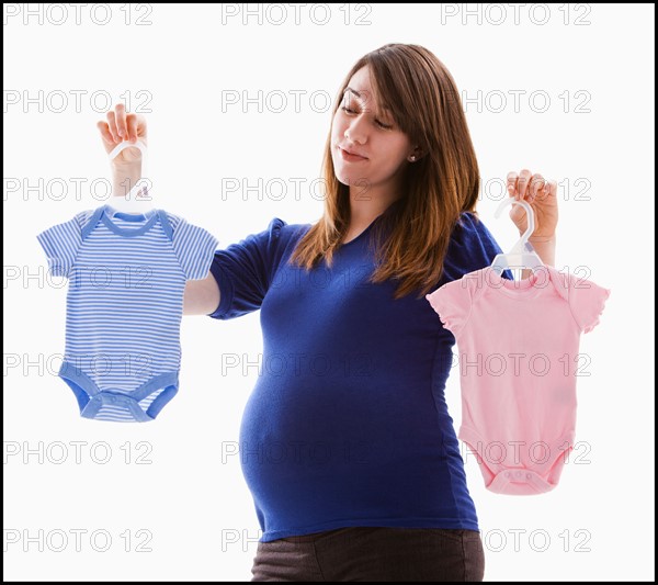 Studio Shot of pregnant woman holing baby onesie. Photo : Mike Kemp