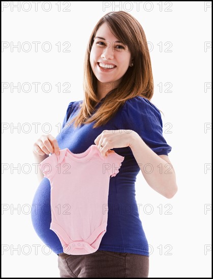 Studio Shot of woman holing baby pink onesie. Photo : Mike Kemp