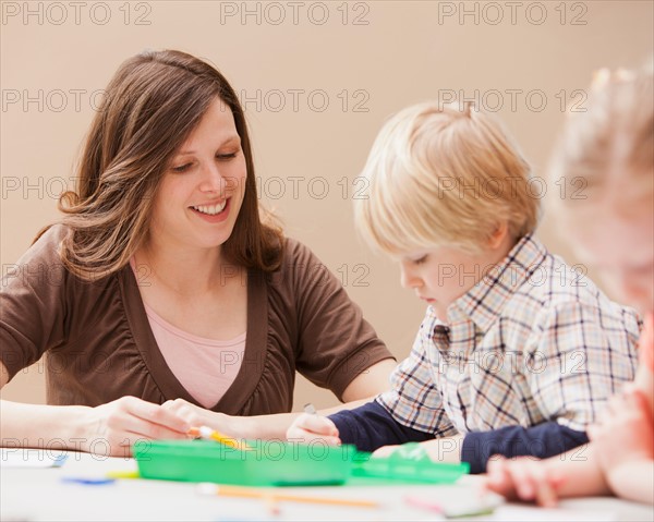 Mid adult woman teaching boy (4-5) drawing in kindergarten. Photo : Mike Kemp