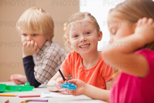 Girl (4-5)  looking at camera during art lesson in kindergarten. Photo : Mike Kemp