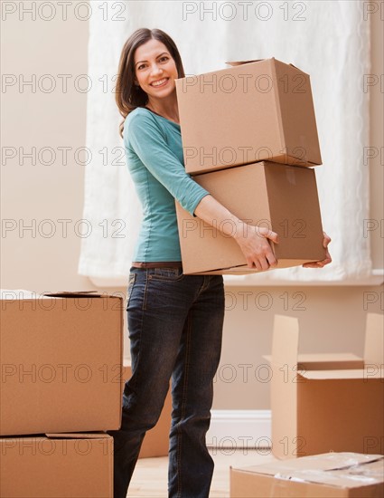 Mid adult woman carrying cardboard boxes. Photo : Mike Kemp