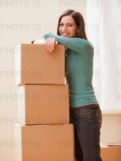 Mid adult woman leaning on cardboard boxes. Photo : Mike Kemp