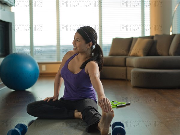 Young woman exercising at home. Photo : Dan Bannister