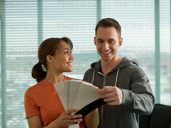 Young couple choosing color from color swatch. Photo : Dan Bannister