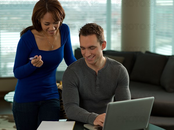 Young couple paying bills at kitchen table. Photo : Dan Bannister