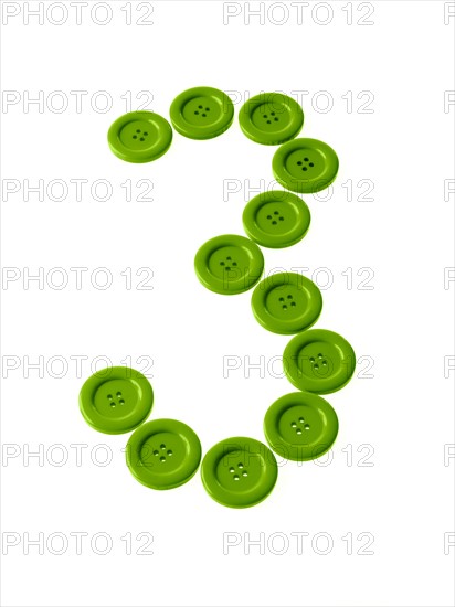 Studio shot of green buttons arranged in number three. Photo : David Arky