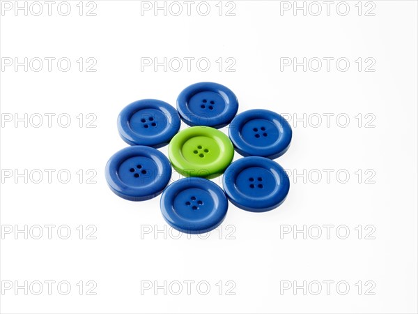 Studio shot of blue and green buttons arranged in flower head. Photo : David Arky