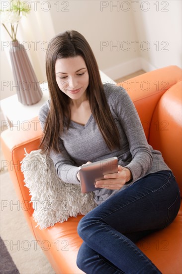 Smiling young woman using digital tablet on sofa. Photo : Rob Lewine