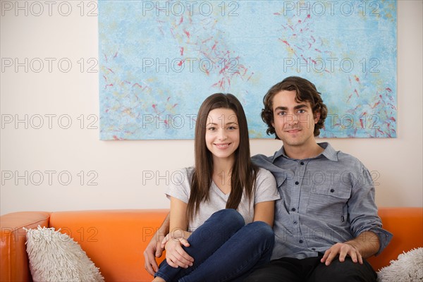 Portrait of young couple sitting on sofa. Photo : Rob Lewine