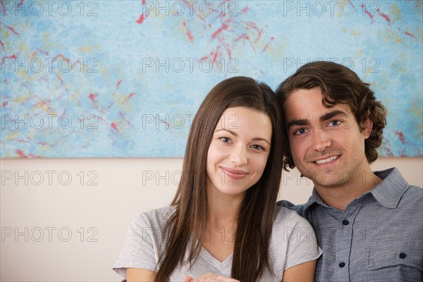 Portrait of young couple sitting on sofa. Photo : Rob Lewine