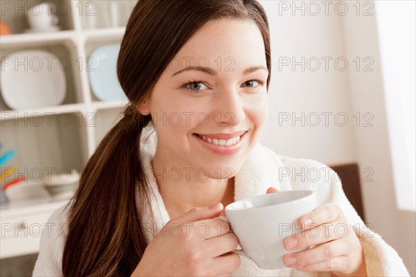 Young smiling woman holding cup. Photo : Rob Lewine