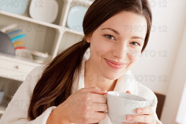 Young smiling woman holding cup. Photo : Rob Lewine