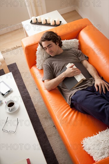 Young man sleeping on sofa. Photo : Rob Lewine