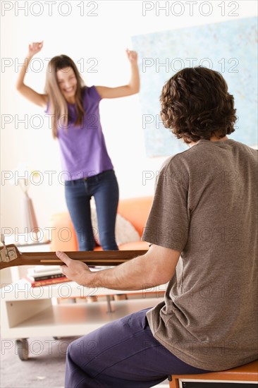 Young man playing electric guitar, young woman dancing in background. Photo : Rob Lewine