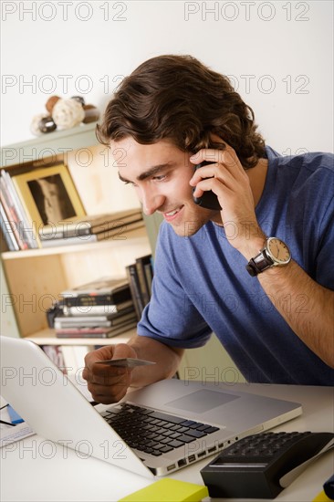 Young man talking via mobile at home. Photo : Rob Lewine