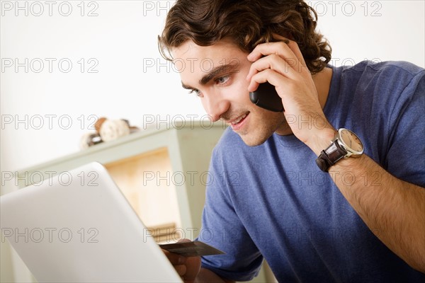 Young man talking via mobile at home. Photo : Rob Lewine