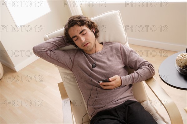 Young man listening music on armchair. Photo : Rob Lewine