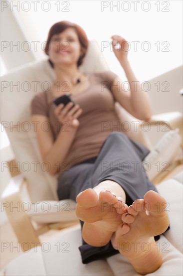 Young woman listening music on armchair. Photo : Rob Lewine