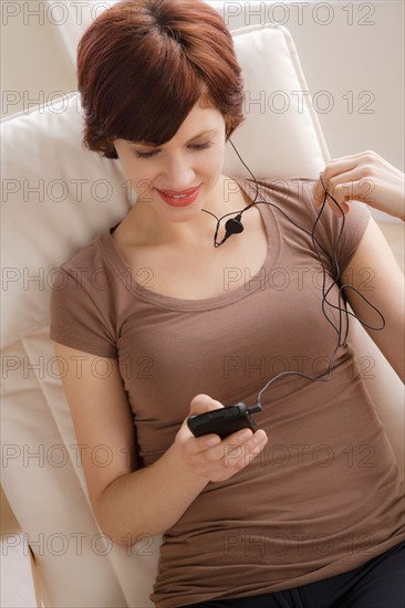 Young woman listening music on armchair. Photo : Rob Lewine